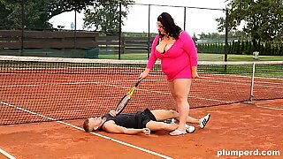 Obese woman facesits on her trainer at the tennis court